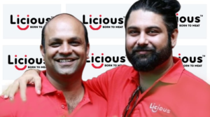 Abhay Hanjura and Vivek Gupta, co-founders of Licious, standing in front of the Licious logo, representing India's leading direct-to-consumer meat and seafood brand.