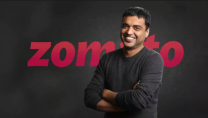 Deepinder Goyal, founder of Zomato, standing in front of the Zomato logo, known for building India's leading food delivery and quick-commerce platform.