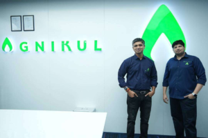 Srinath Ravichandran and Moin S.P.M., founders of Agnikul Cosmos, standing at the company's headquarters with the Agnikul logo, India's pioneering private space startup.